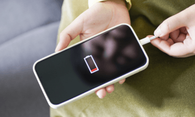 Rozładowany telefon z ikoną baterii podłączany do ładowarki